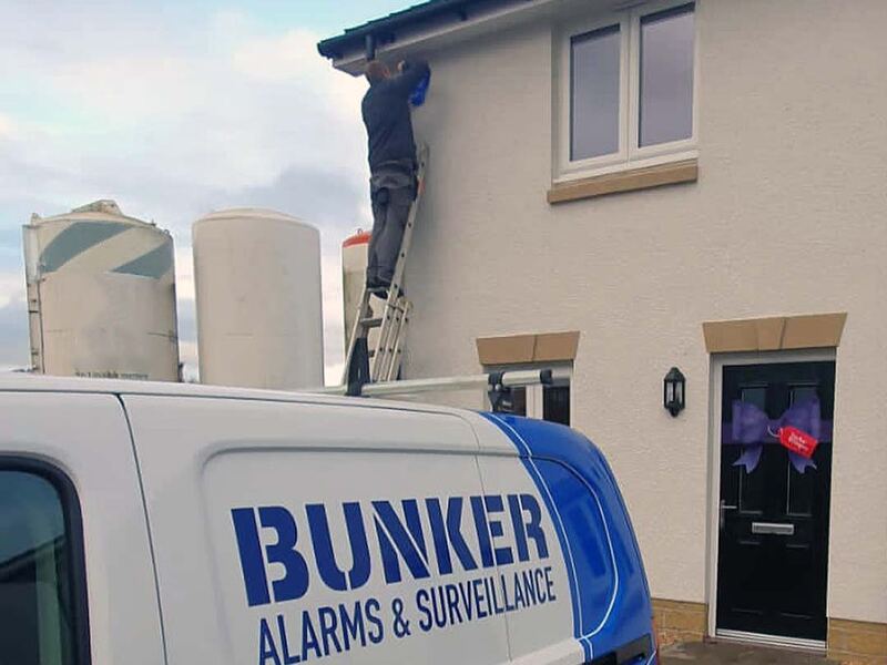 Engineer fitting an alarm device to a wall